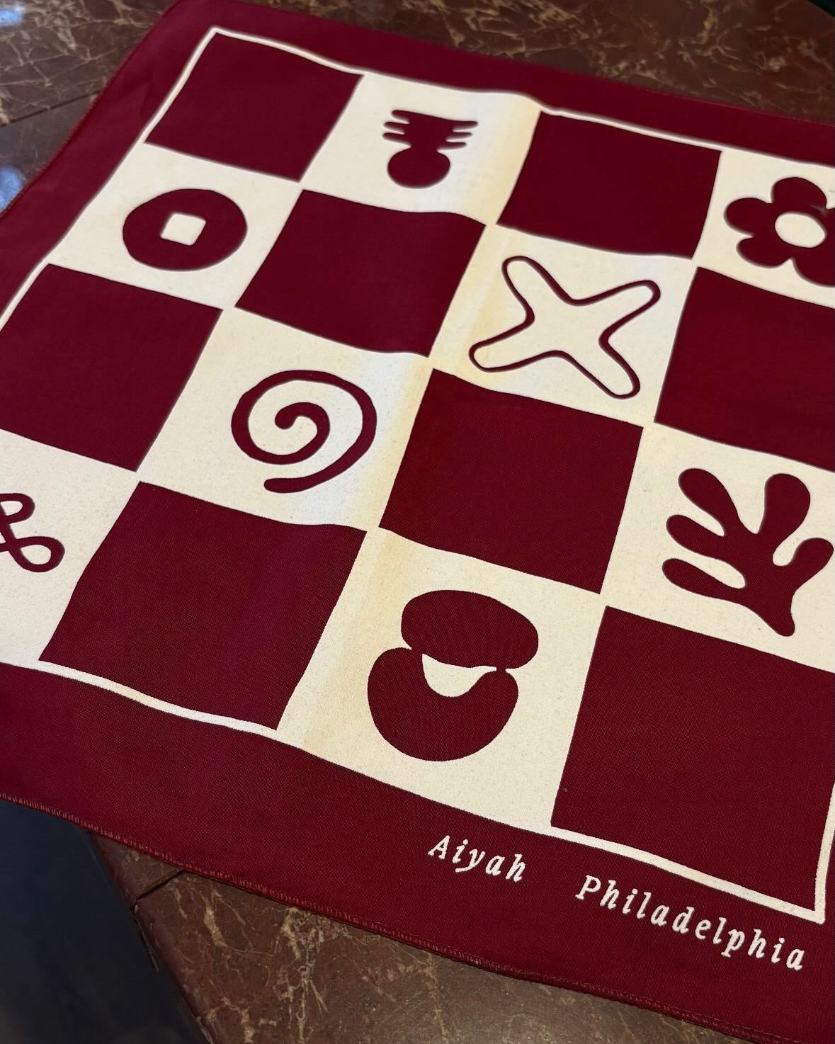 Red and white checkered bandana with symbols on a dark surface