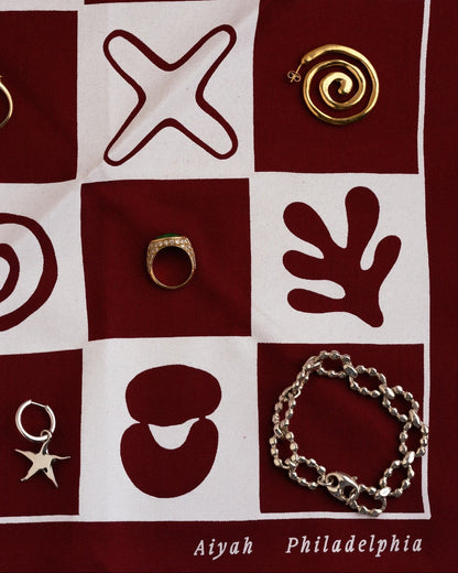 Jewelry displayed on a checkered bandana with patterns and text.