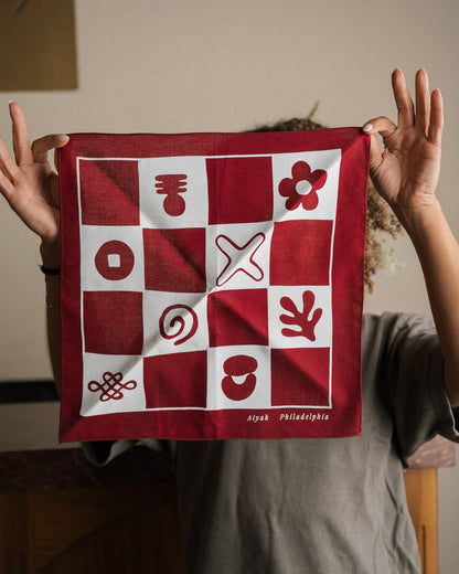 Red and white bandana towel with symbols held by a person